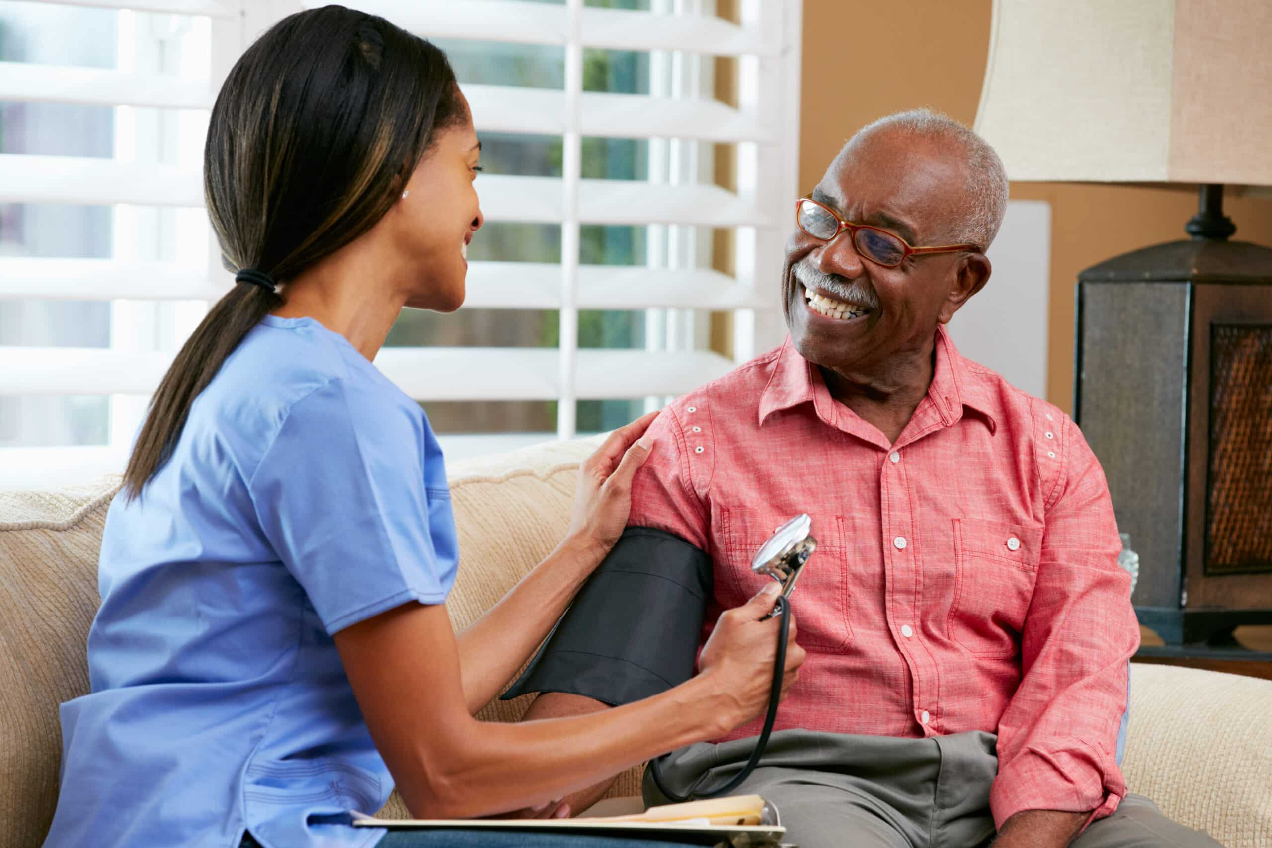 Nurse taking blood pressure of patient on couch
